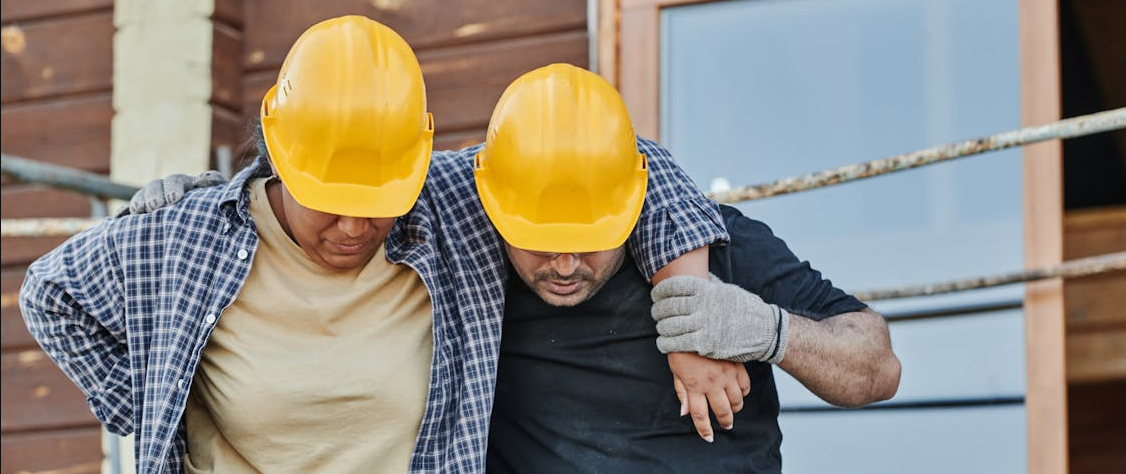 Injured worker holding their wrist while sitting at a worksite, representing workplace injury.